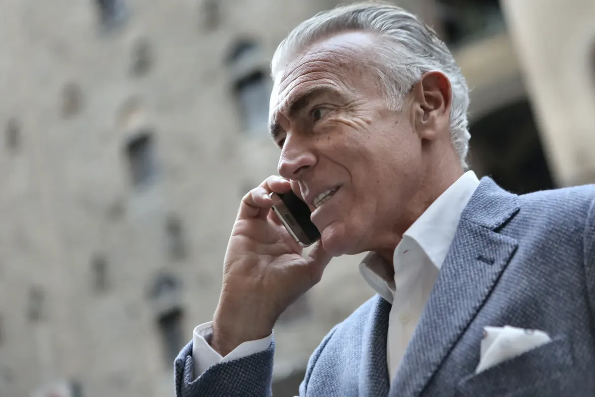 Confident senior man in a suit talking on his smartphone outdoors during the day.
