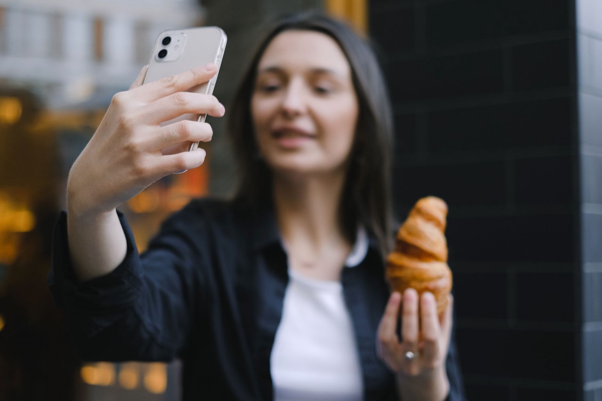 Italian influencer holding smartphone in a busy street